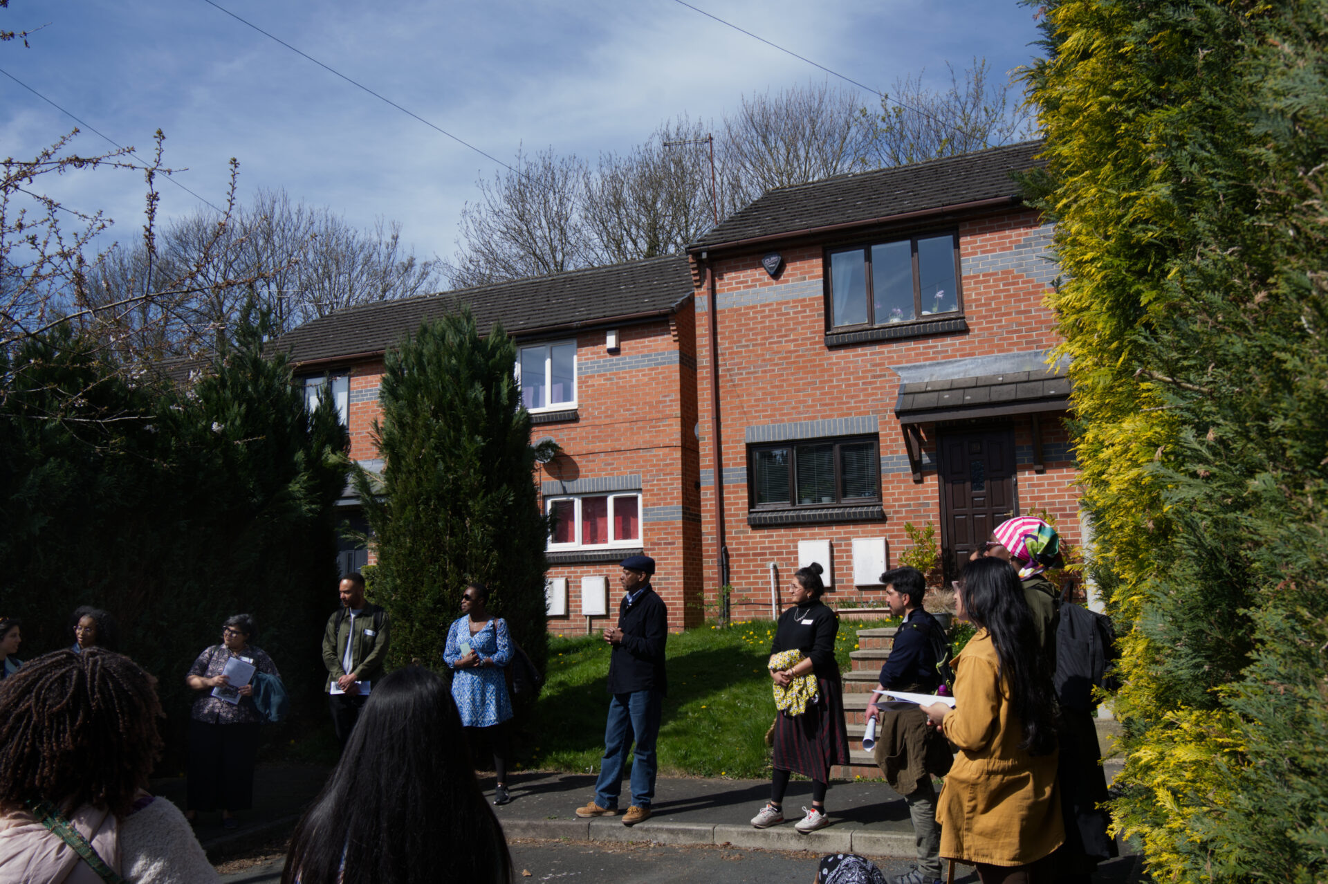 A group of global majority people standing in front of self-build properties