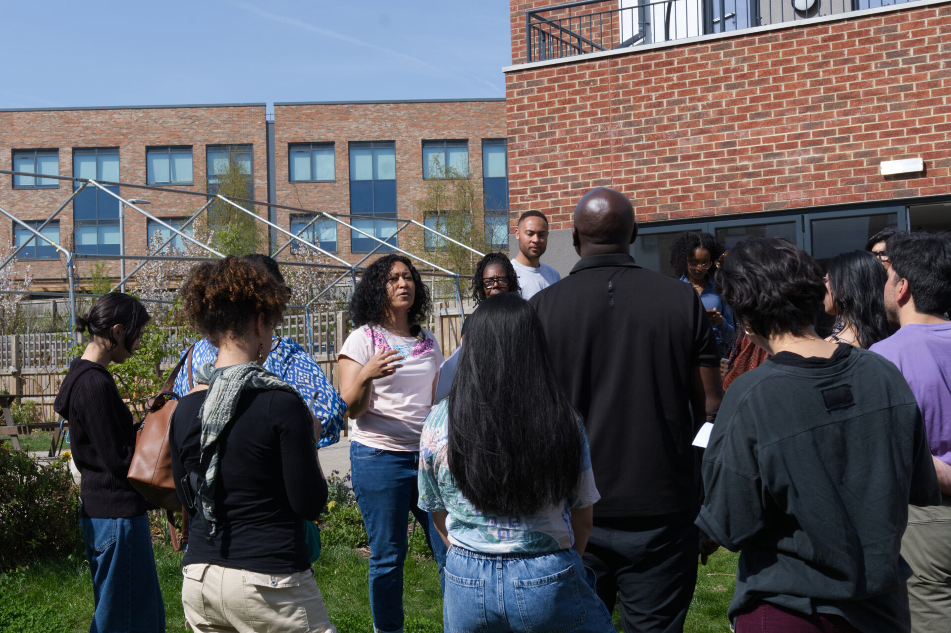 Cynthia Brathwaite speaking, surrounded by a group of global majority people.