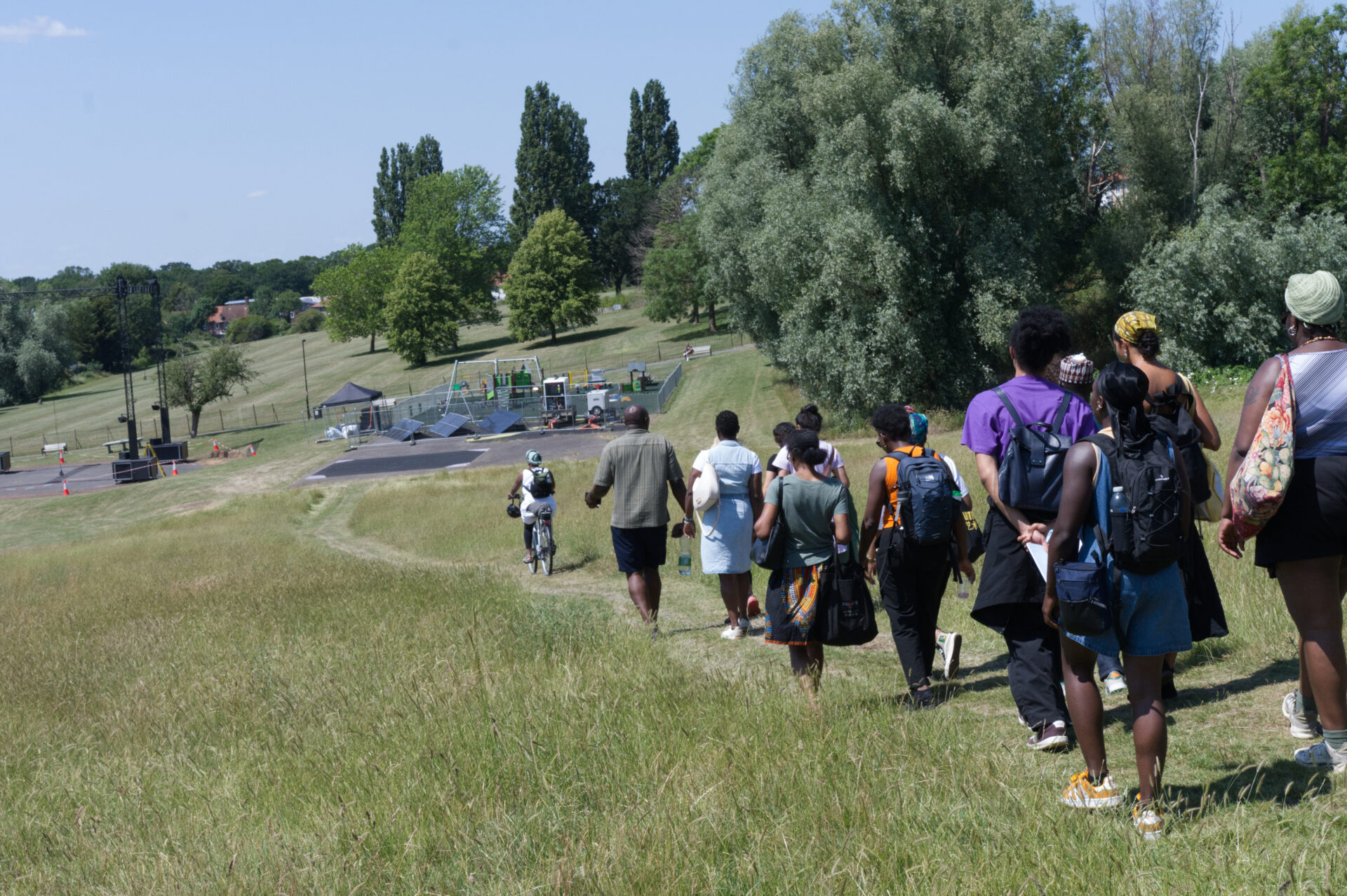 A group of global majority people walking through a park, away from the camera